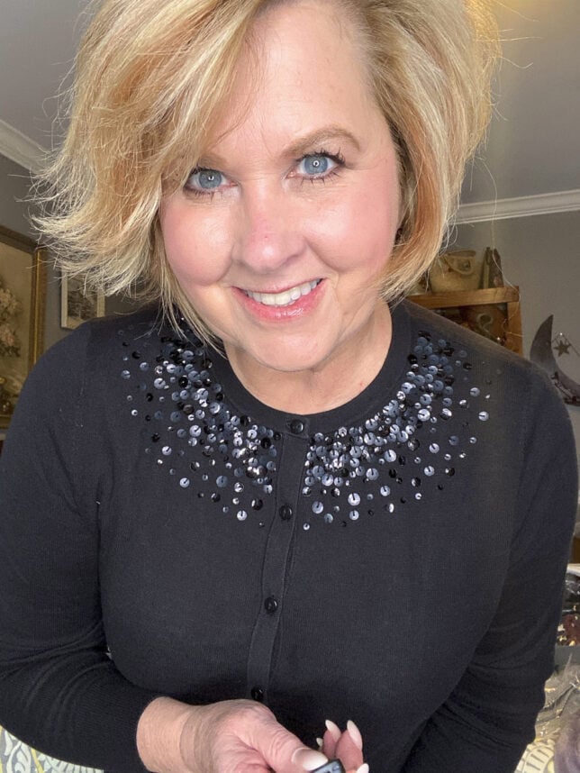 Fashion Blogger 50 Is Not Old holds a try on session shows the black sequins on a black sweater