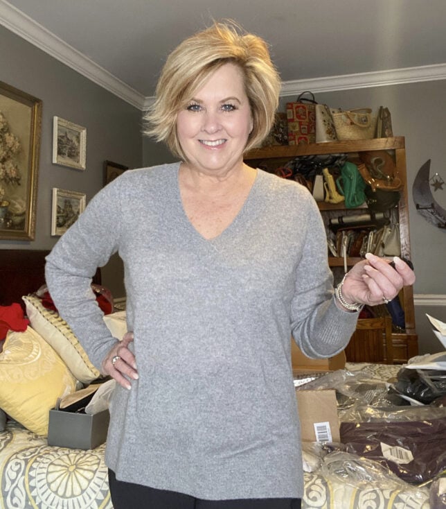 Fashion Blogger 50 Is Not Old holds a try on session with a gray cashmere v-neck sweater
