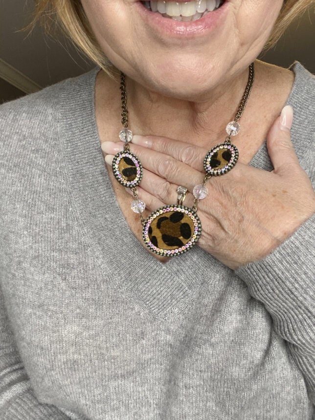 Fashion Blogger 50 Is Not Old holds a try on session shows an up close view of a leopard print necklace