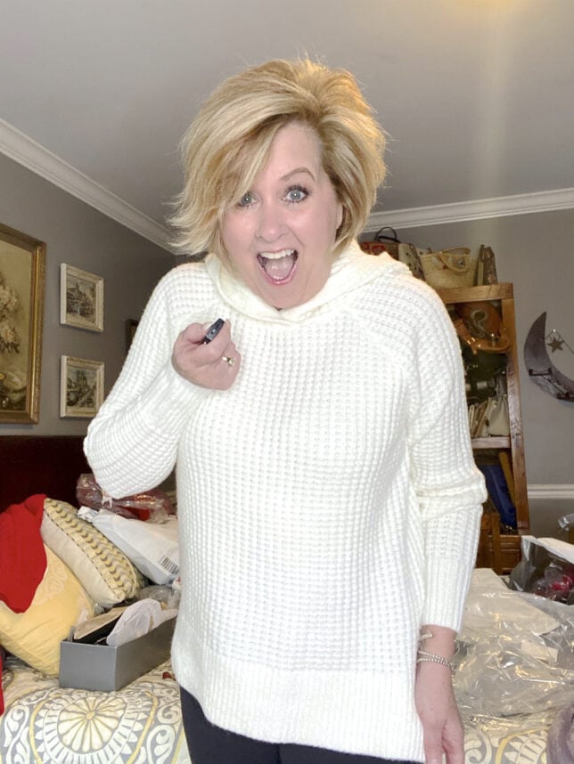 Fashion Blogger 50 Is Not Old holds a try on session with a waffle knit sweater in ivory