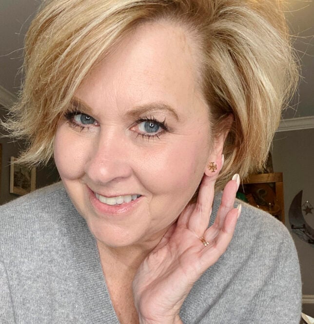 Fashion Blogger 50 Is Not Old holds a try on session and shows a tiny Tory Burch earring