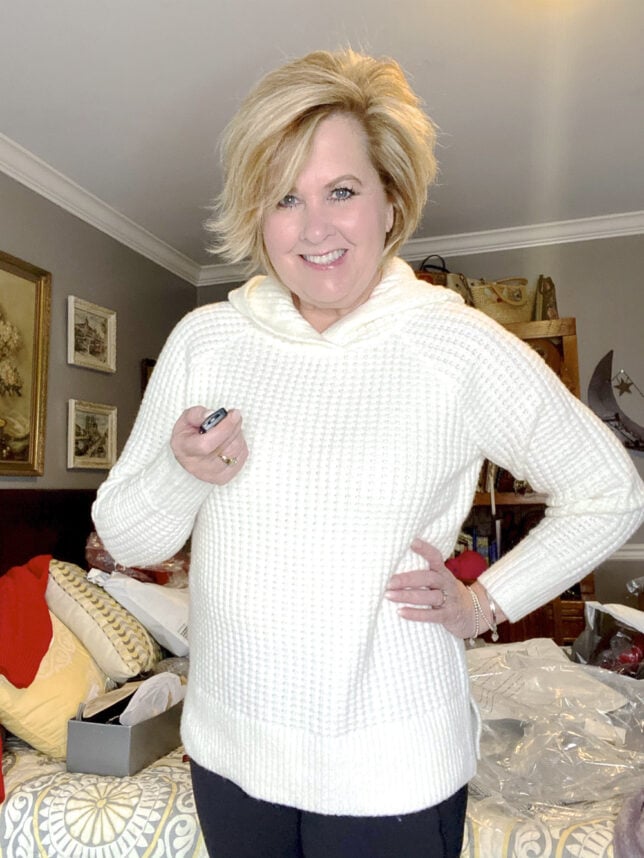 Fashion Blogger 50 Is Not Old holds a try on session with an ivory waffle knit sweater