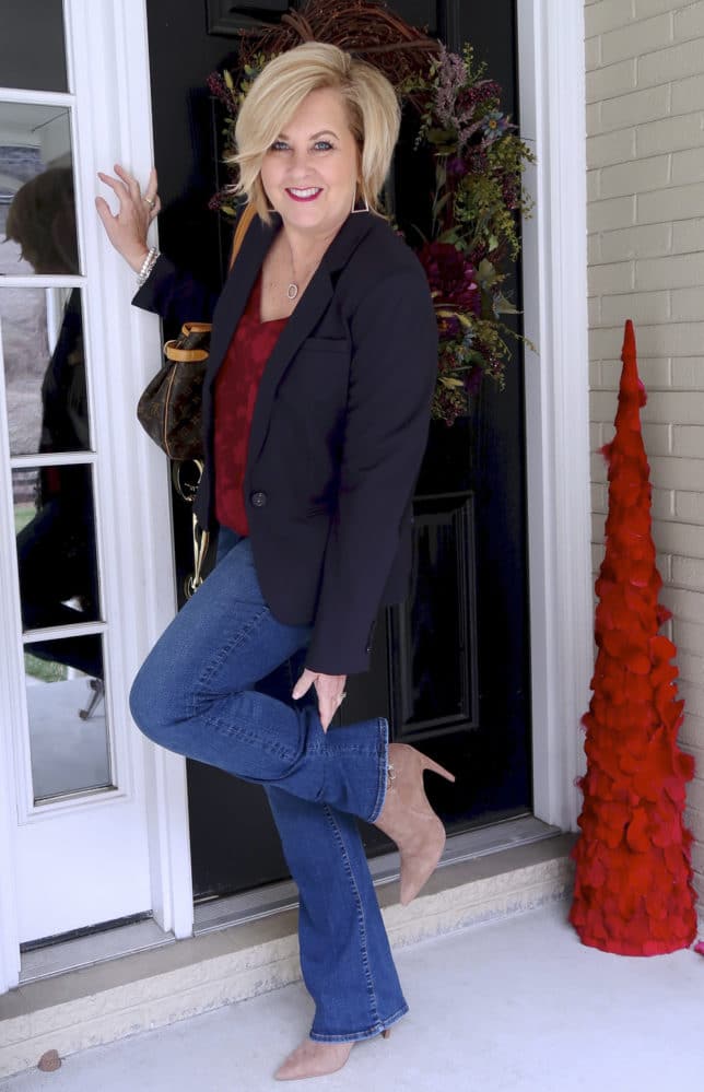 Flare jeans, pointy ankle boots, a floral burgundy camisole, and a navy blazer worn by fashion blogger 50 is not old