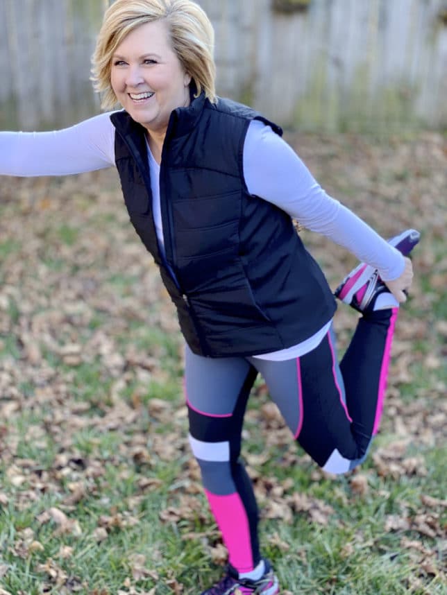 Fashion Blogger 50 Is Not Old wearing Avia leggings and a quilted vest from Walmart stretching her leg