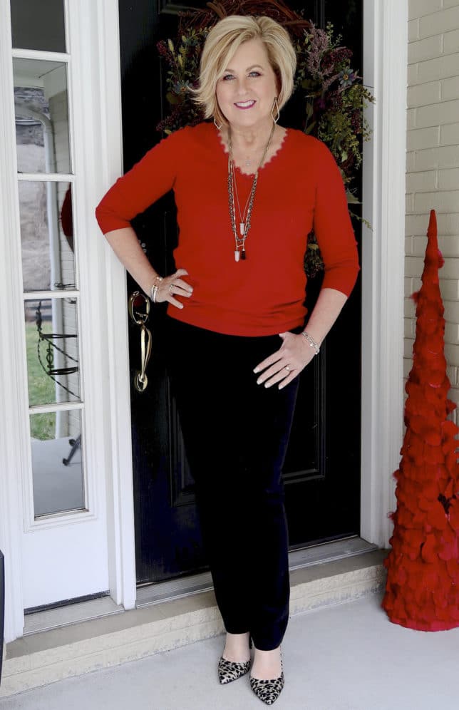 Fashion Blogger 50 Is Not Old is wearing a red v-neck sweater and black velveteen pants