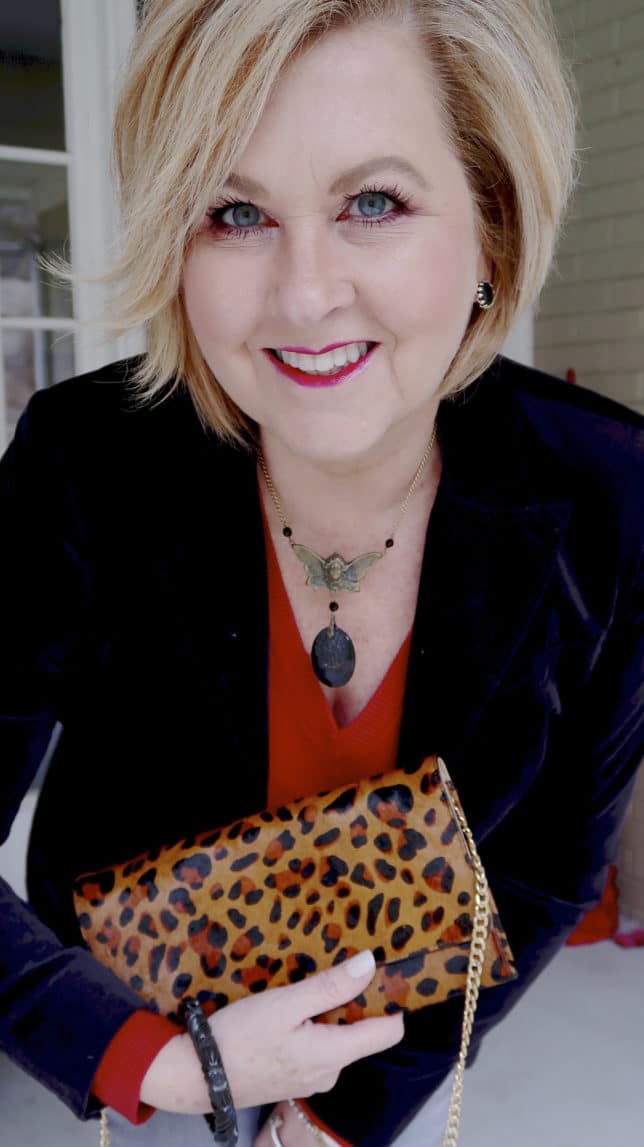 A Black velvet jacket, a red v neck sweater with a leopard clutch from Fashion Blogger 50 Is Not Old