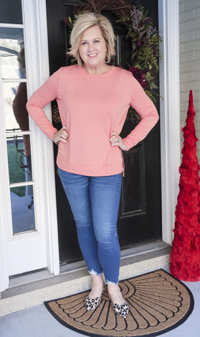 Fashion Blogger 50 Is Not Old is wearing a rose/coral tunic top and a pair of chewed hem jeans and leopard flats