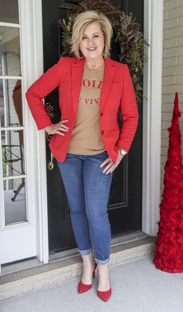 Fashion Blogger 50 Is Not Old wearing a red blazer and a tan sweater with cuffed jeans and red pumps