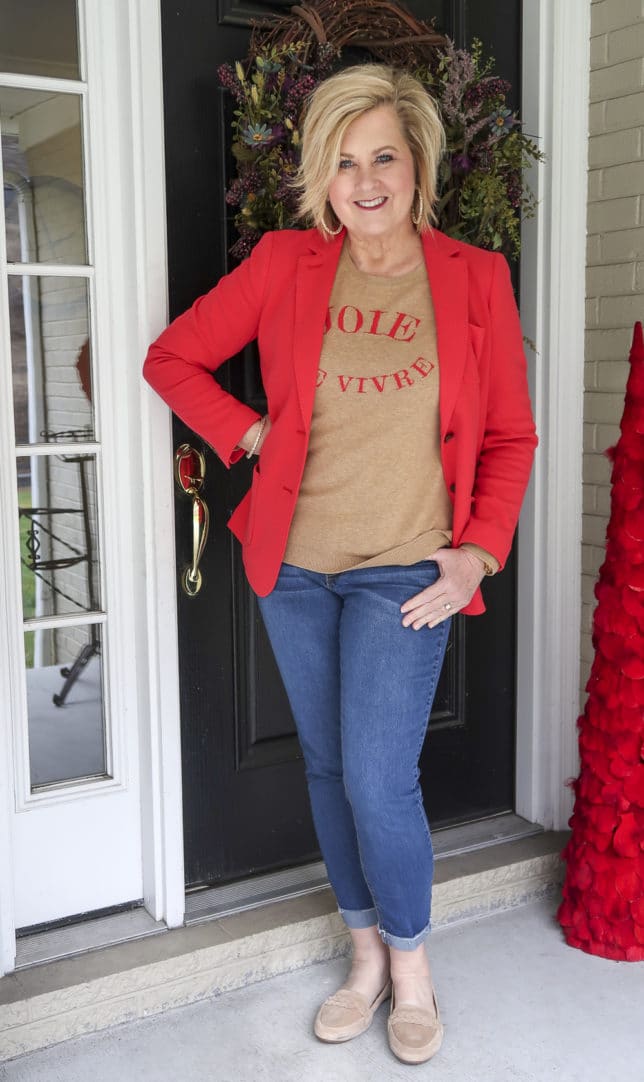 Fashion Blogger 50 Is Not Old wearing a red blazer and a tan sweater with cuffed jeans and suede loafers