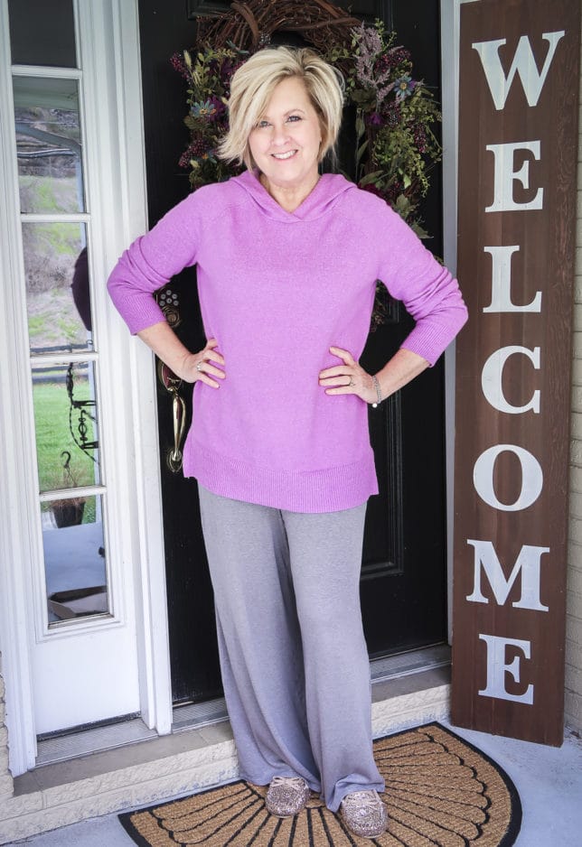 Fashion Blogger 50 Is Not Old wearing a lilac sweater, a pair of gray lounge pants, and glittery house shoes