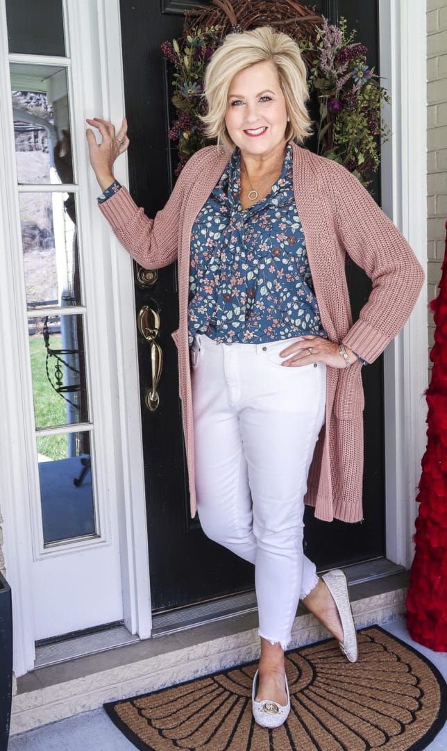 Fashion Blogger 50 Is Not Old is wearing white jeans before Memorial Day with a blue floral blouse, a chunky knit cardigan, and white loafers by Michael Kors