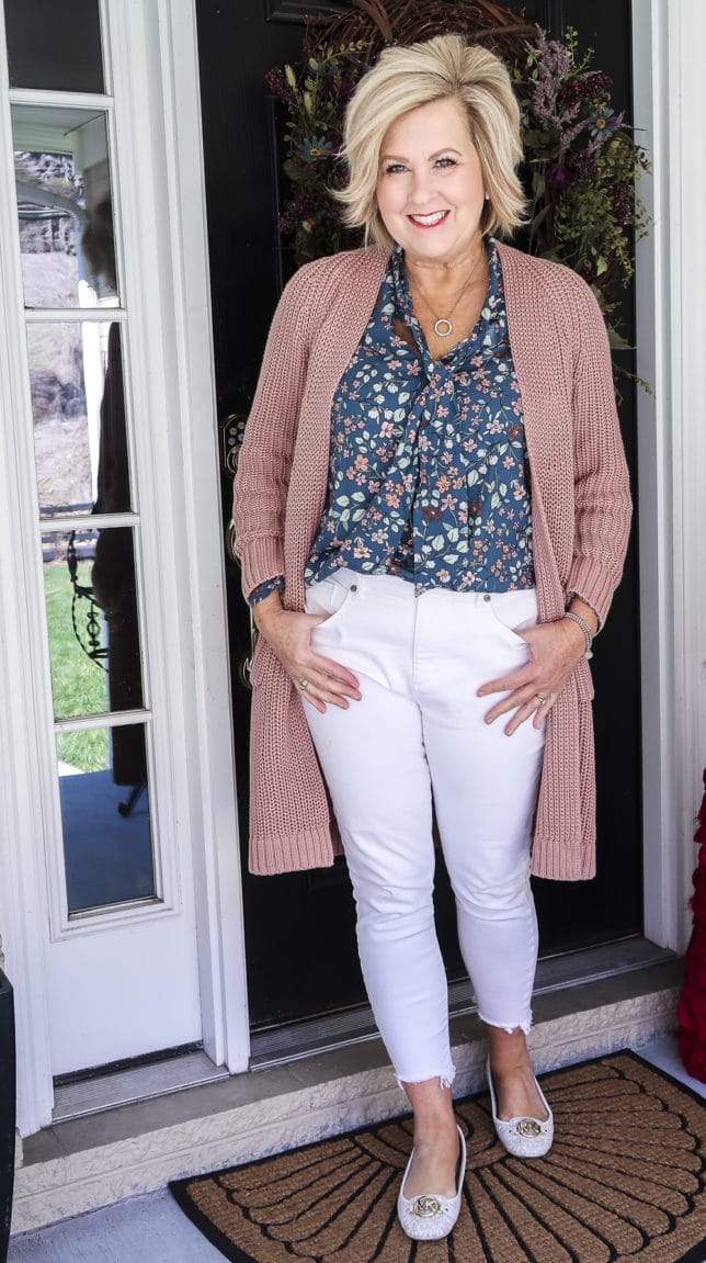 Fashion Blogger 50 Is Not Old is wearing white jeans before Memorial Day with a blue floral blouse and a chunky knit cardigan