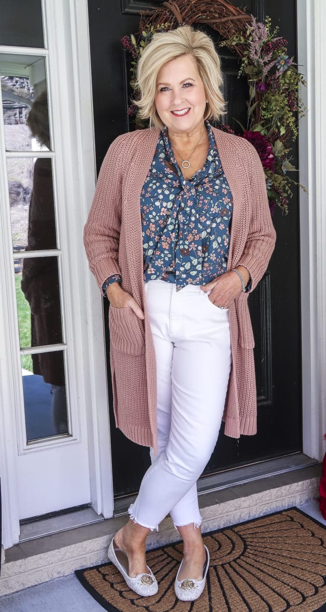 Fashion Blogger 50 Is Not Old is wearing white jeans before Memorial Day with a blue floral blouse, a chunky knit cardigan, and white loafers