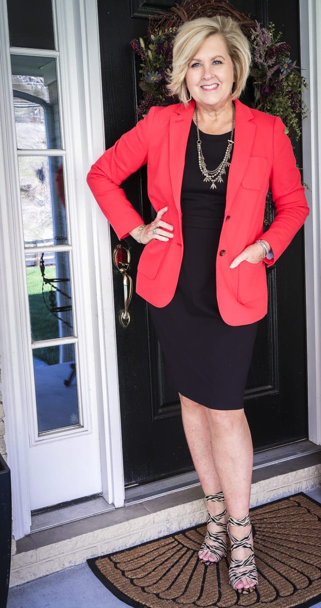 Fashion Blogger 50 Is Not Old is wearing a little black dress, a apple red Pique Knit blazer, and strappy animal print heels
