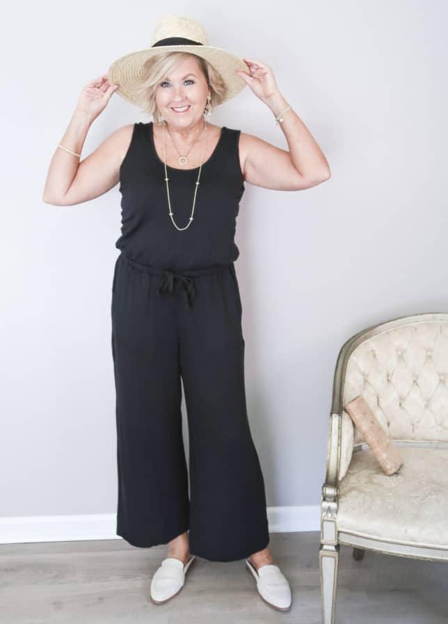 50 Is Not Old is wearing a black sleeveless wide leg jumper with a straw hat and linen mules