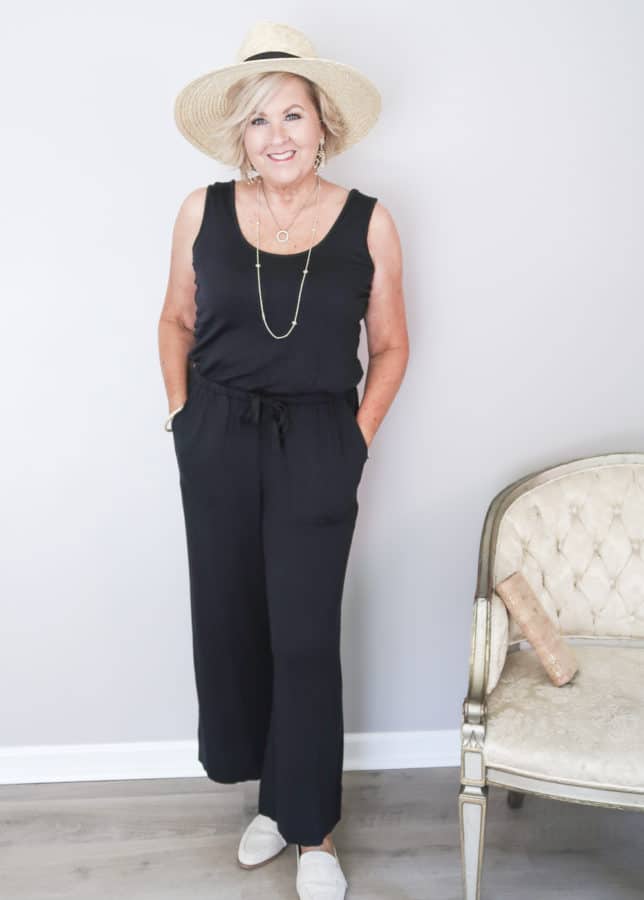 50 Is Not Old is wearing a black sleeveless wide leg ankle length jumper with a straw hat and linen mules