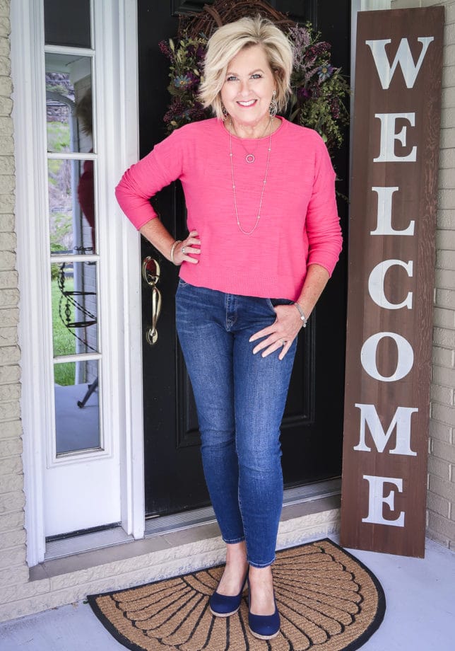 Fashion Blogger 50 Is Not Old is wearing a casual outfit. A pink crop sweater, skinny ankle jeans, and navy slingback espadrilles
