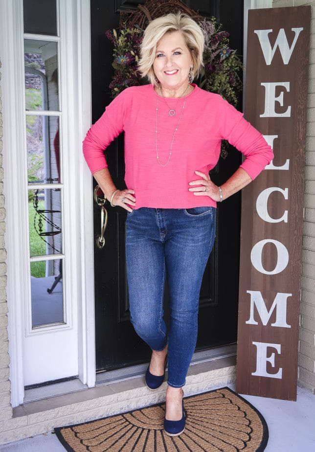 Fashion Blogger 50 Is Not Old is wearing a casual outfit. A pink crop sweater, skinny jeans, and navy slingback espadrilles