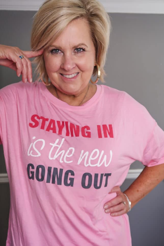 Fashion Blogger 50 Is Not Old wearing a pink shirt that says, Staying in is the new going out.