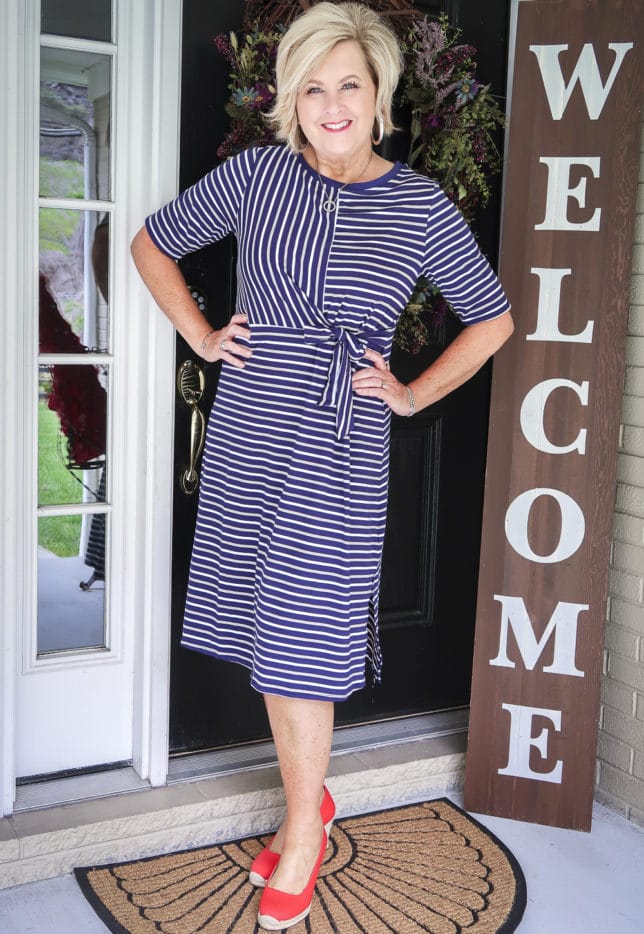 50 Is not Old is wearing a navy striped faux wrap dress with bright red espadrilles from J. Crew