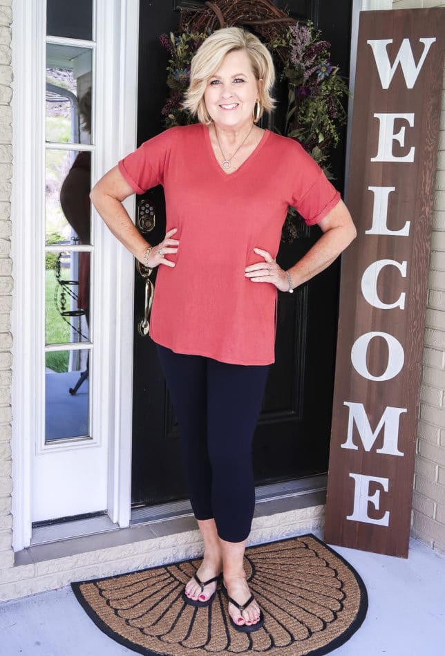 Fashion Blogger 50 Is Not Old is a relaxing rose colored v-neck tunic tee, navy Ponte knit leggings, and black flip flops by Tory Burch.
