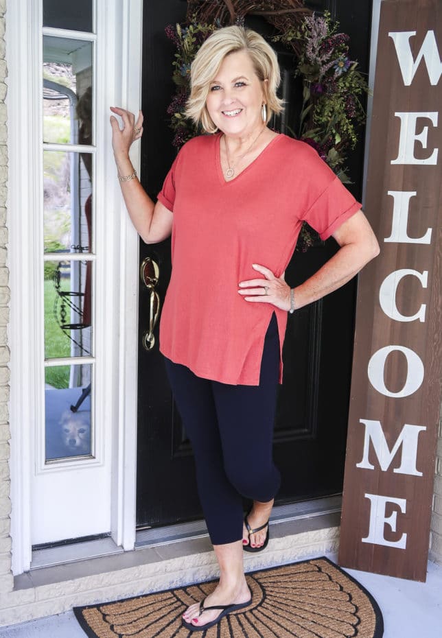 Fashion Blogger 50 Is Not Old is a relaxing rose colored v-neck tunic tee, navy Ponte knit leggings, and flip flops by Tory Burch.
