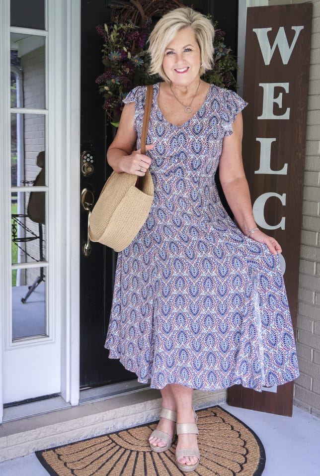 Fashion Blogger 50 Is Not Old wearing a gorgeous v-neck printed dress from Scoop, and round straw bag, and metallic gold espadrille sandals all available at Walmart