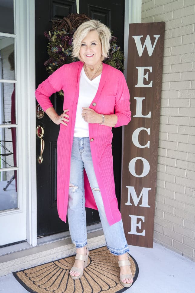Fashion Blogger 50 Is Not Old is looking sharp with this hot pink duster cardigan, distressed jeans, and white t-shirt