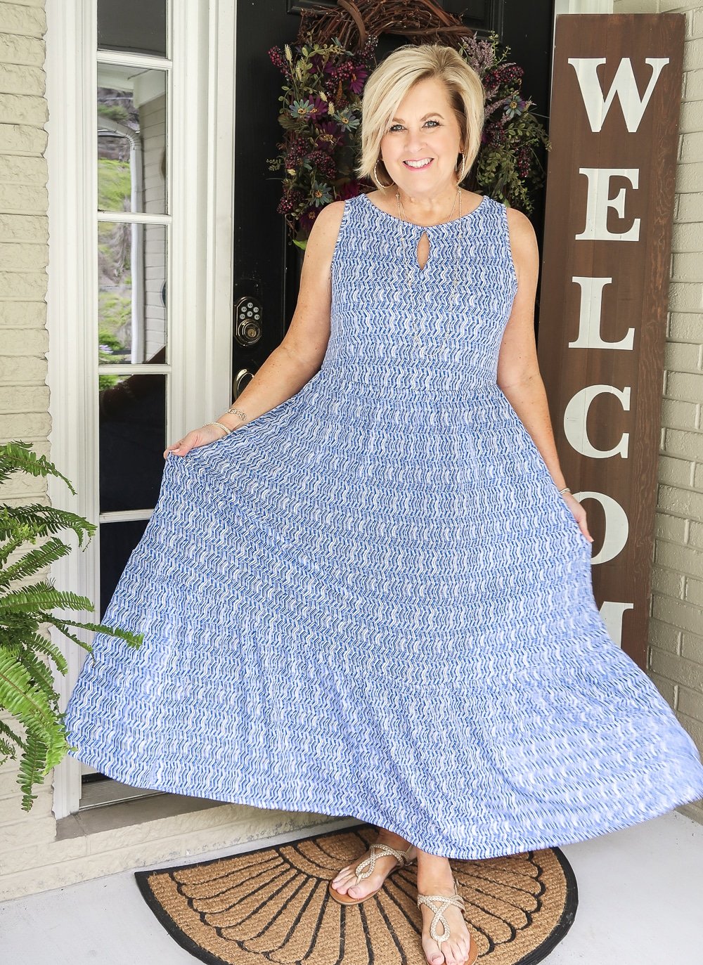 Fashion Blogger 50 Is Not Old wearing a blue and white tiered sleeveless maxi dress with gold braided sandals from Target