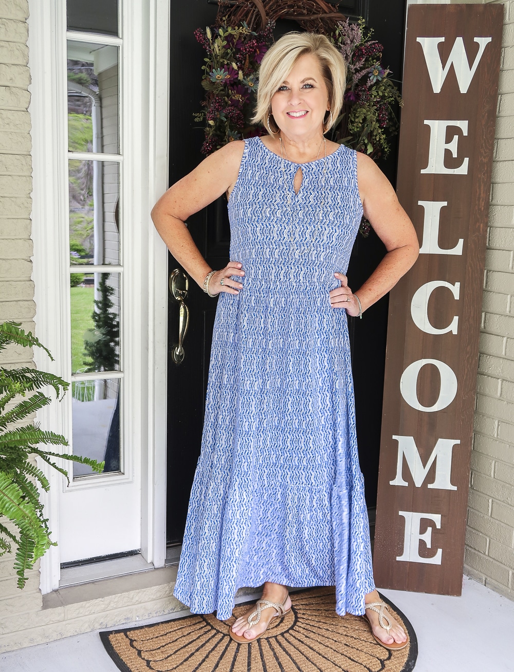 Fashion Blogger 50 Is Not Old wearing a blue and white tiered sleeveless maxi dress with gold sandals from Target