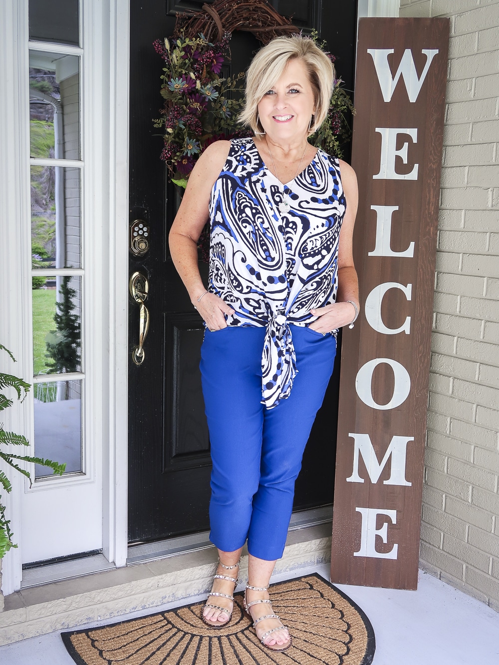 Fashion Blogger 50 Is Not Old wearing a bright cobalt blue paisley top and blue pants with tan sandals with spikes from Steve Madden