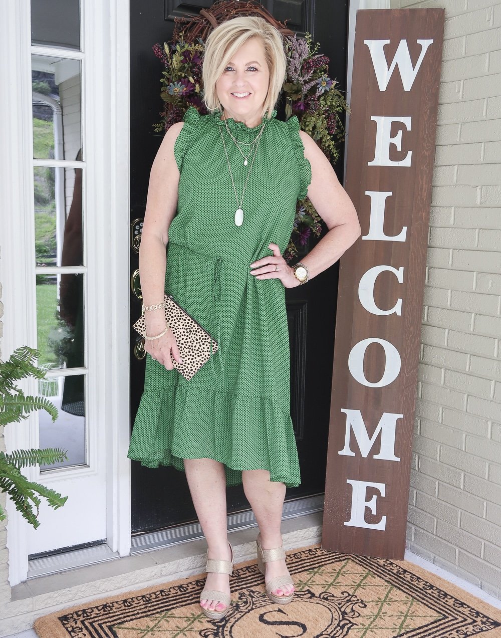 Fashion Blogger 50 Is Not Old is wearing a polka dotted dress that has a high neck and ruffles plus gold wedge shoes