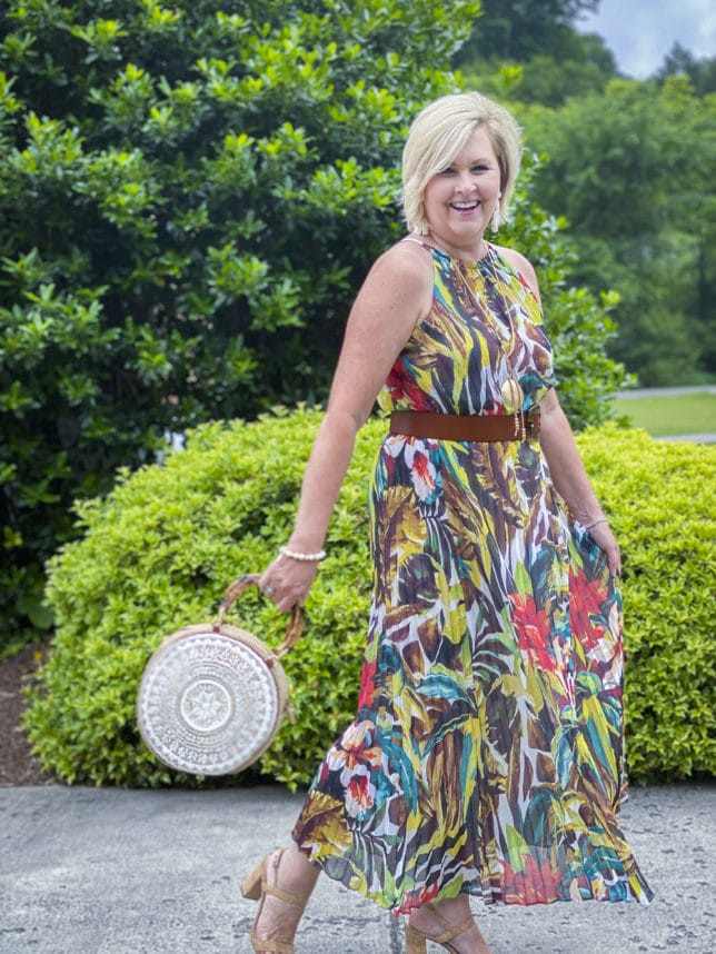 Fashion Blogger 50 Is Not Old is ready for an indoor wedding in this colorful tropical midi dress with a shell handbag