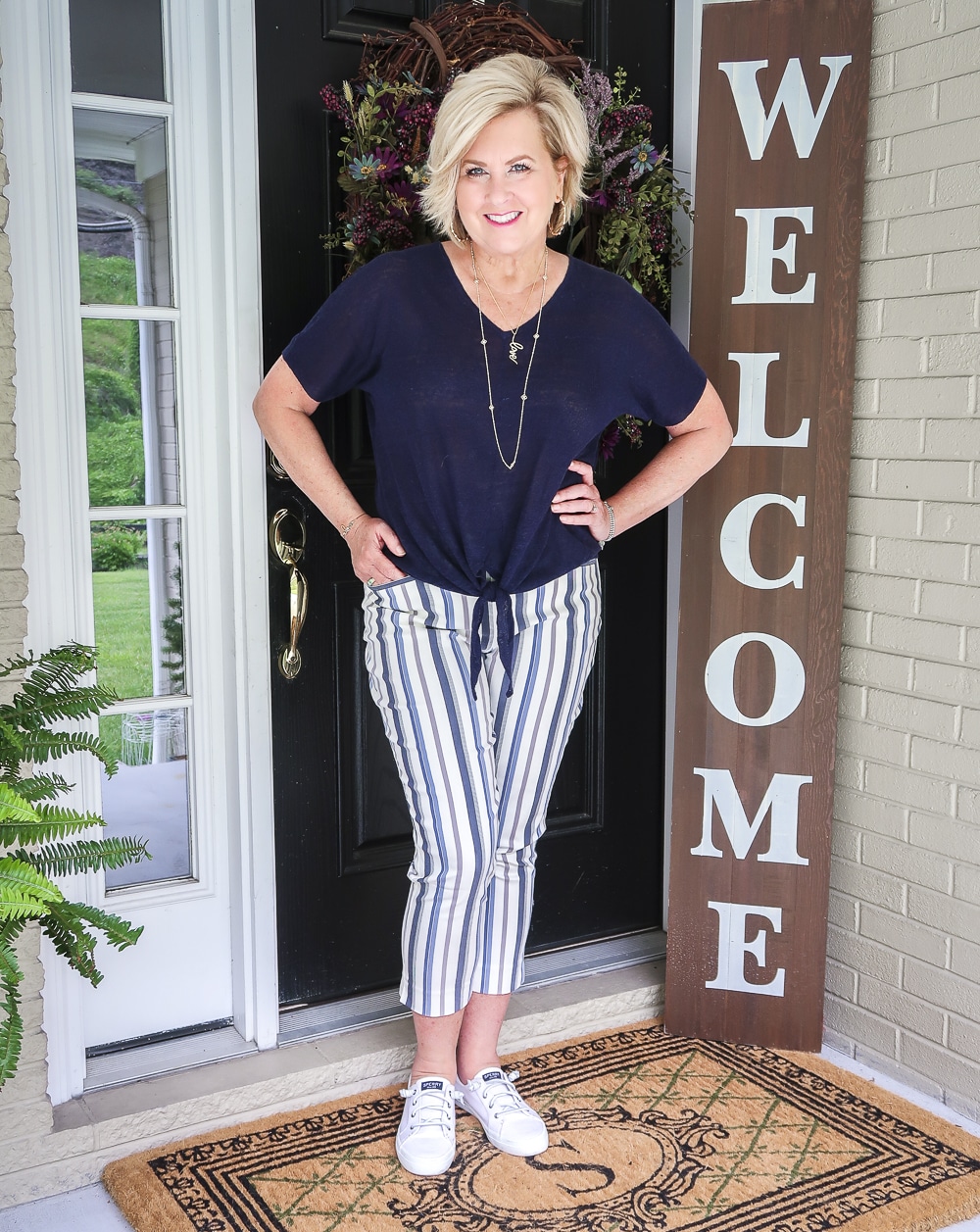 Fashion Blogger 50 Is Not Old is wearing a navy tie front top with striped crop pants and white sneakers