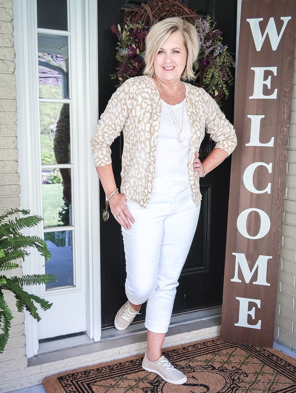 Fashion Blogger 50 Is Not Old wearing an all white outfit with a neutral leopard print cardigan and linen slip on sneakers