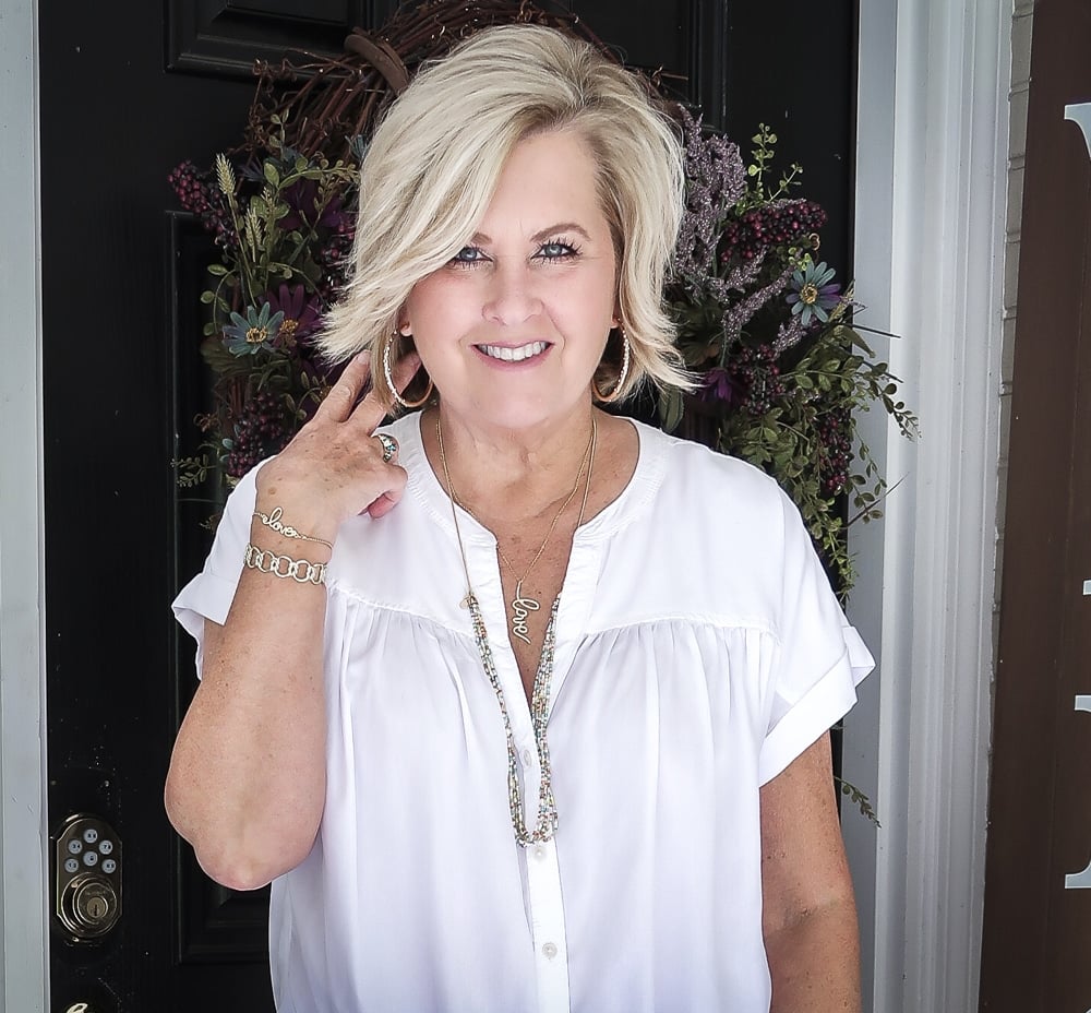 Fashion Blogger 50 Is Not Old is wearing a white tie-front top with gold jewelry