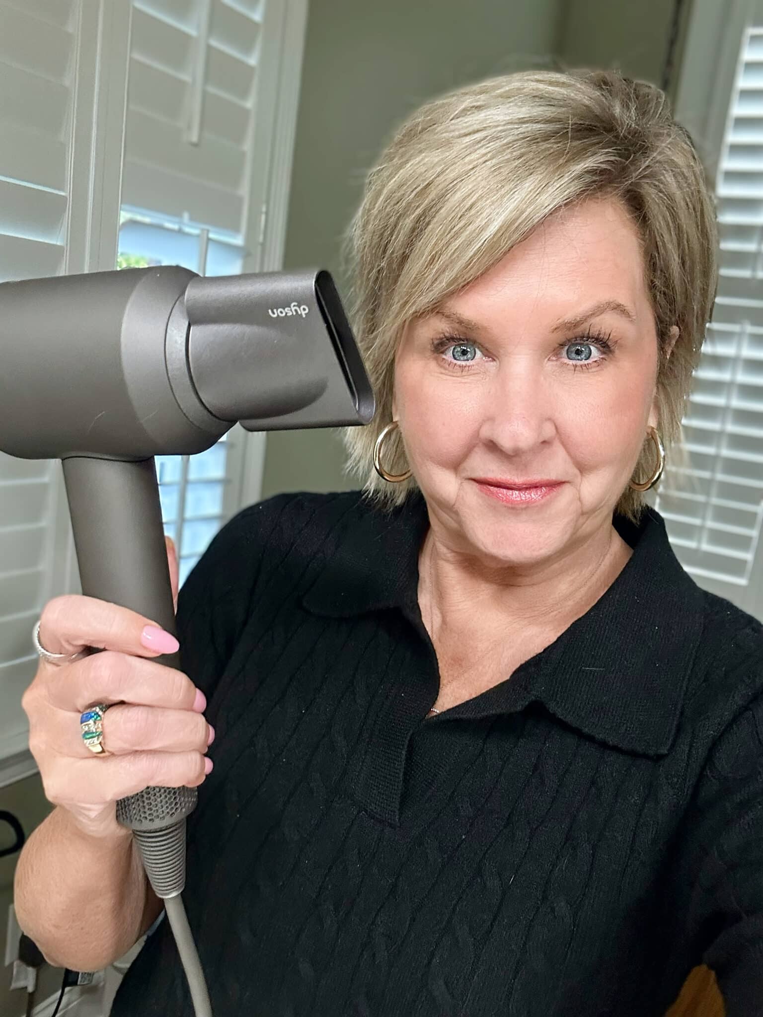 Over 50 Fashion Blogger, Tania Stephens is holding a few of her favorite things, a Dyson hairdryer.