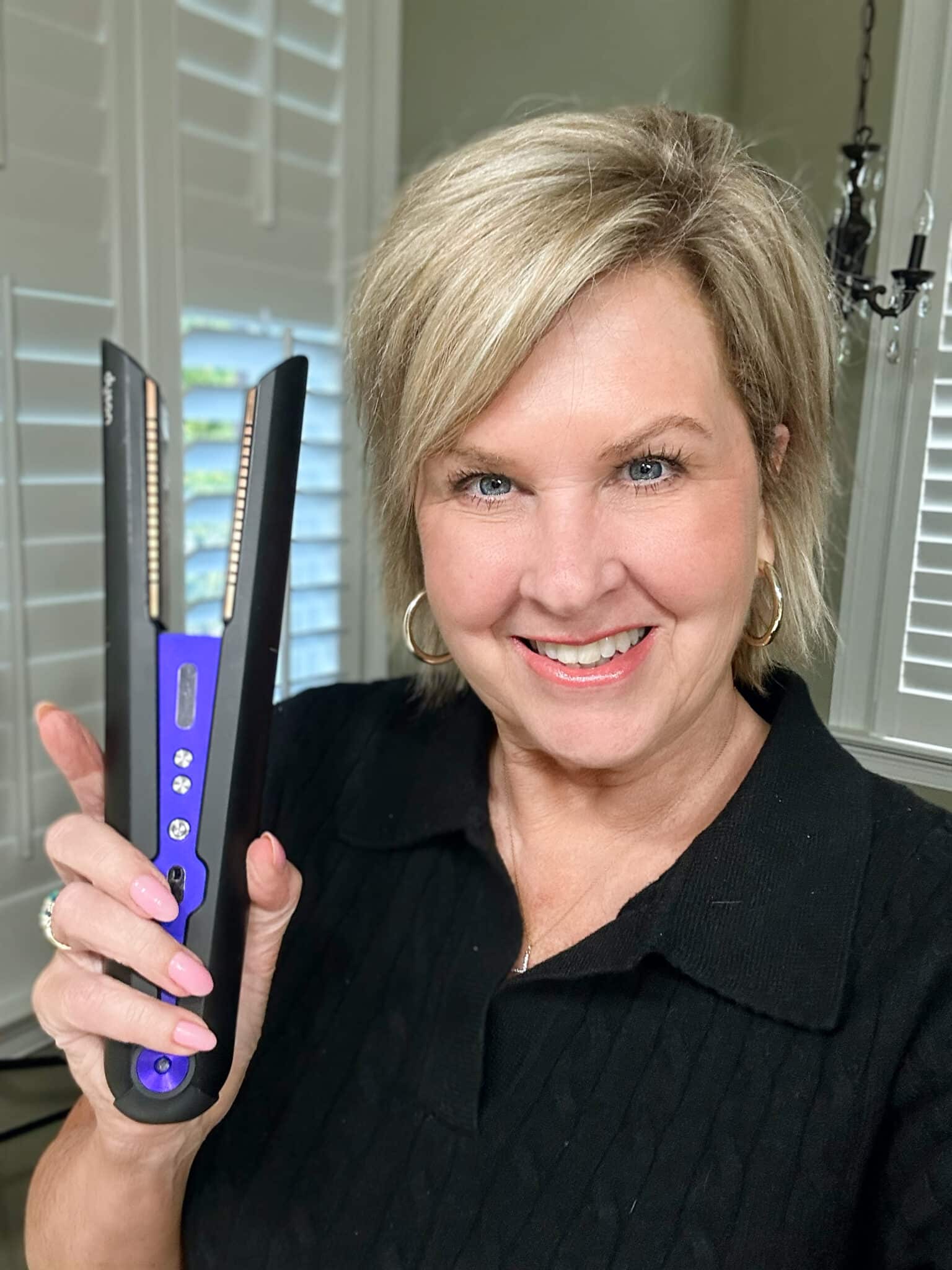 Over 50 Fashion Blogger, Tania Stephens is holding a few of her favorite things, a Dyson Straightener