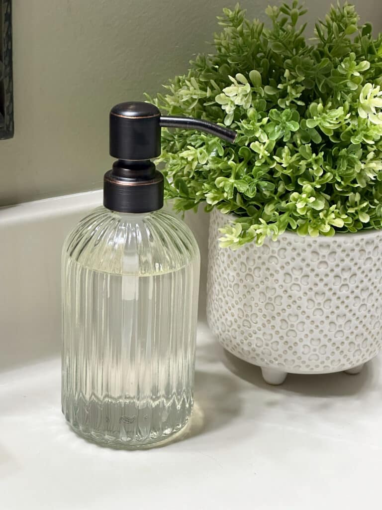 Over 50 Fashion Blogger, Tania Stephens is holding a few of her favorite things, a soap dispenser