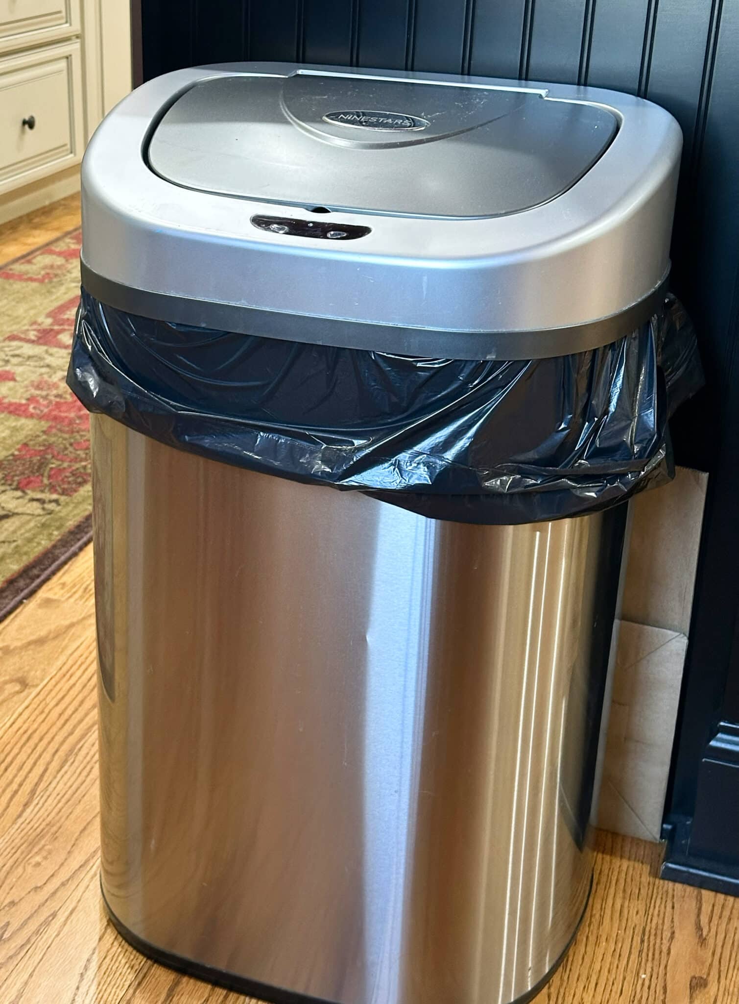 Over 50 Fashion Blogger, Tania Stephens is holding a few of her favorite things, a battery operated trash can