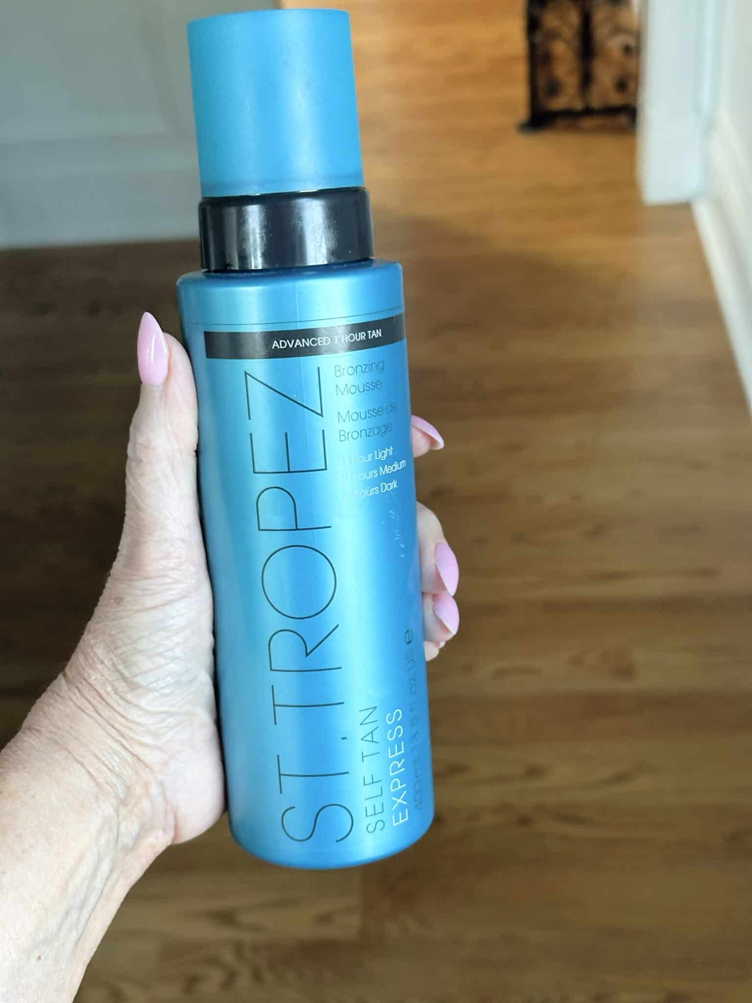 Over 50 Fashion Blogger, Tania Stephens is holding a few of her favorite things, a St. Tropez self tanner.