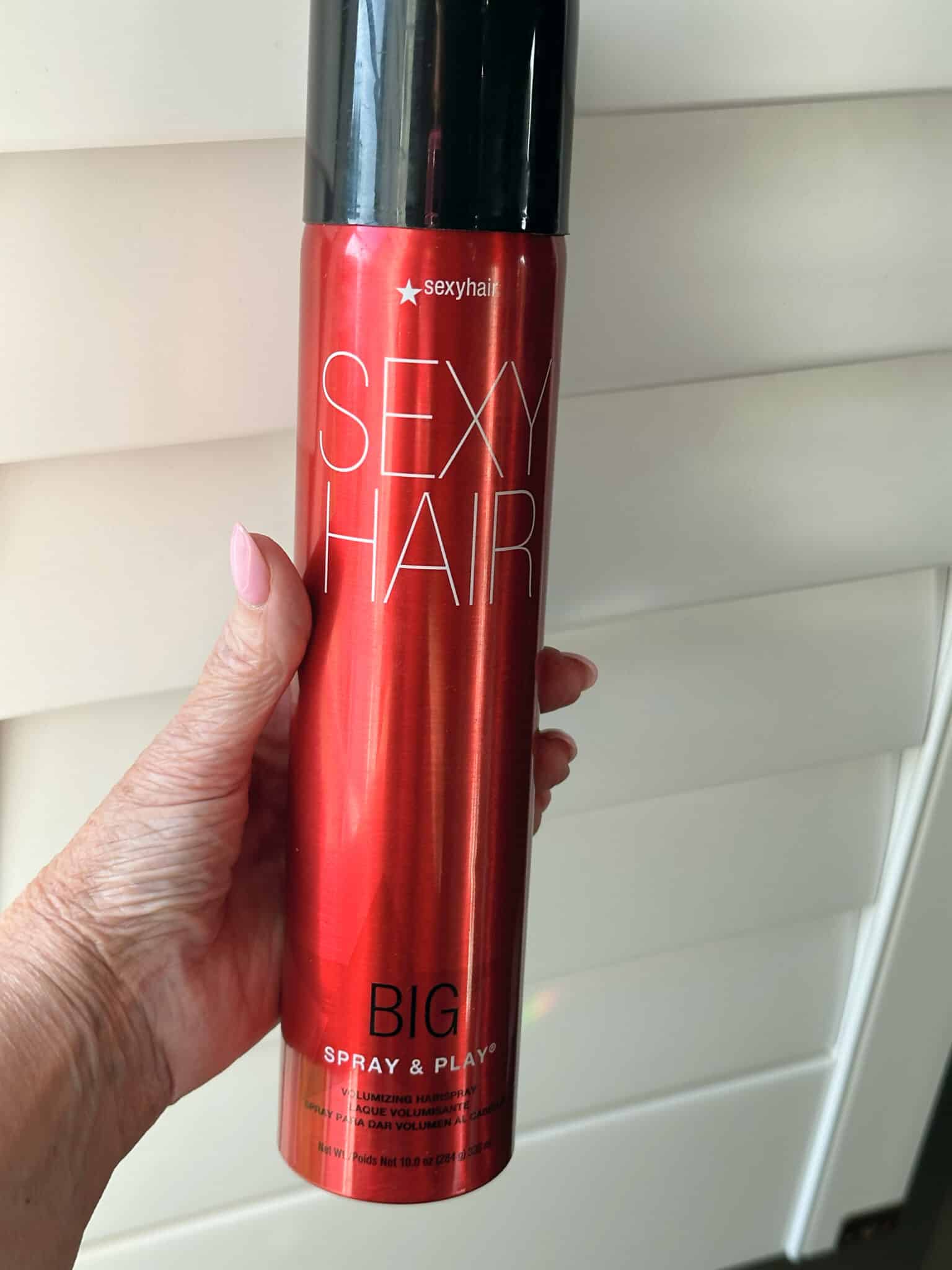 Over 50 Fashion Blogger, Tania Stephens is holding a few of her favorite things, a Big Sexy hairspray