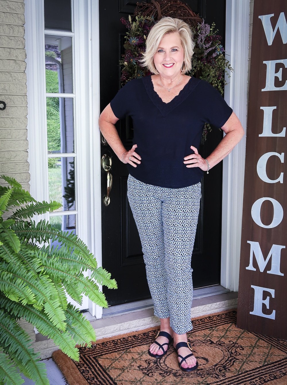Fashion Blogger 50 Is Not Old wearing a dark navy linen top with a lace neckline and blue printed ankle pants with navy sandals