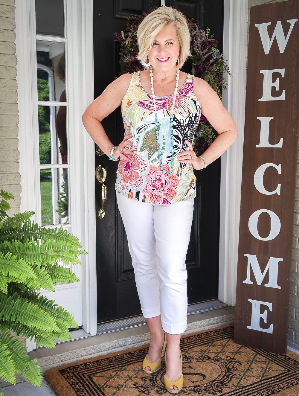 Fashion Blogger 50 Is Not Old is looking summery in an aqua cardigan, a bright tropical tank top with turquoise jewelry, white ankle jeans, and yellow espadrilles