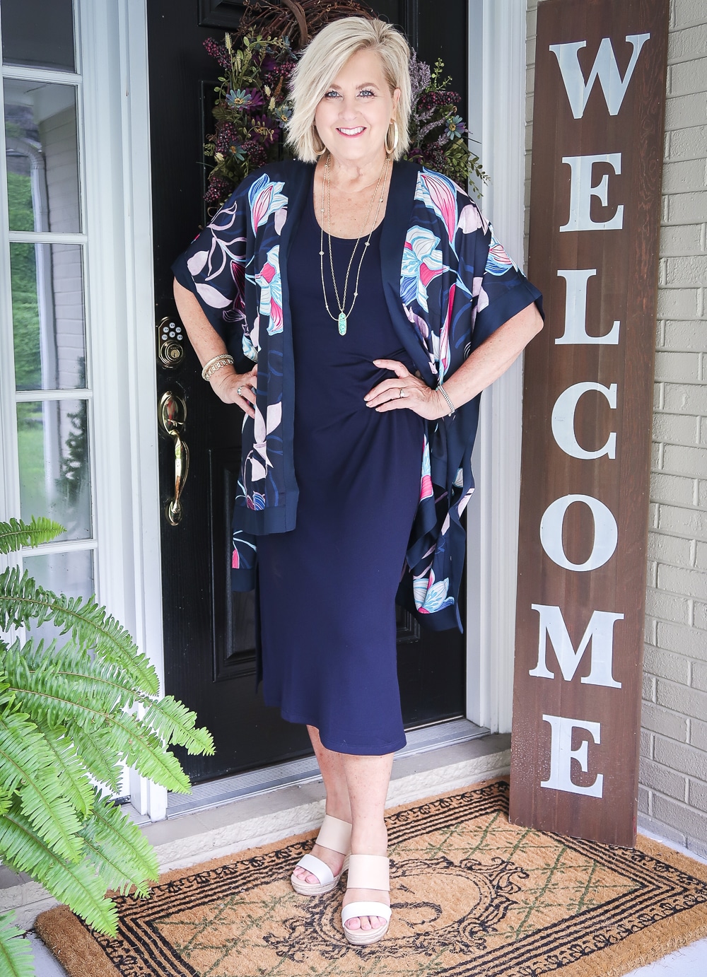 Fashion Blogger 50 Is Not Old is wearing a navy midi dress in all of the seasons. In summer, she added a floral kimono, and two-tone espadrille wedge shoes