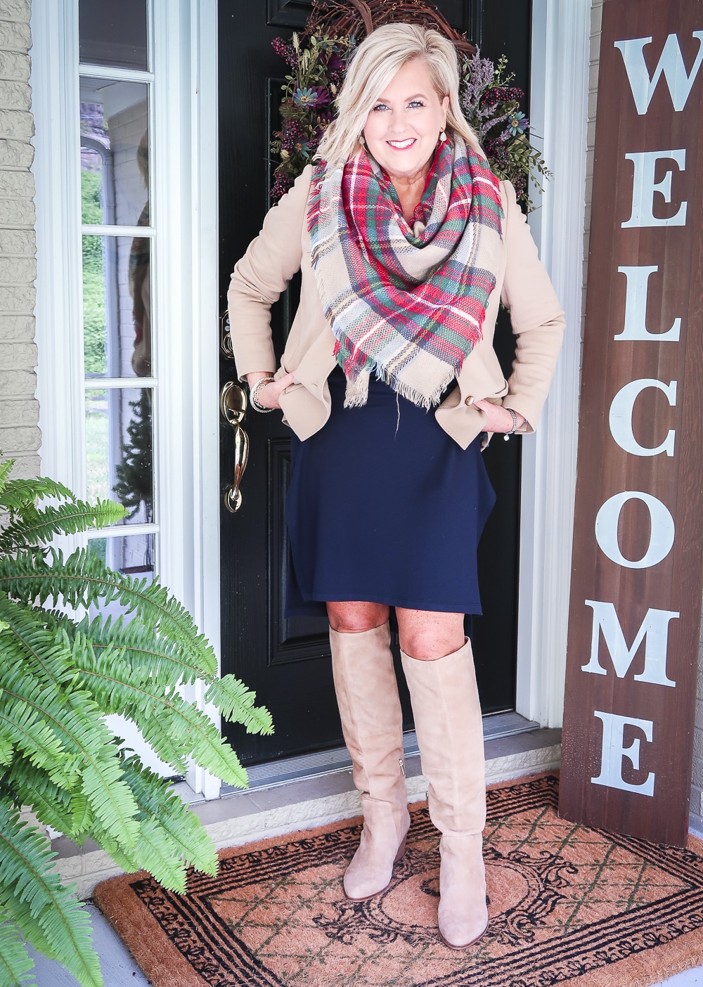 Fashion Blogger 50 Is Not Old is wearing a navy midi dress a tan blazer, a blanket scarf, and tan knee boots