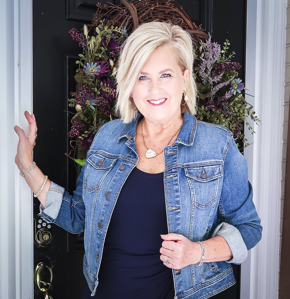 Fashion Blogger 50 Is Not Old is wearing a navy midi dress in all of the seasons. In the fall of the year, she added a denim jacket and gold jewelry from Kendra Scott