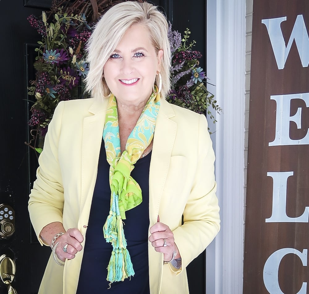 Fashion Blogger 50 Is Not Old is wearing a navy midi dress in all of the seasons. In the spring of the year, she added a pale lemon yellow blazer and a bright scarf