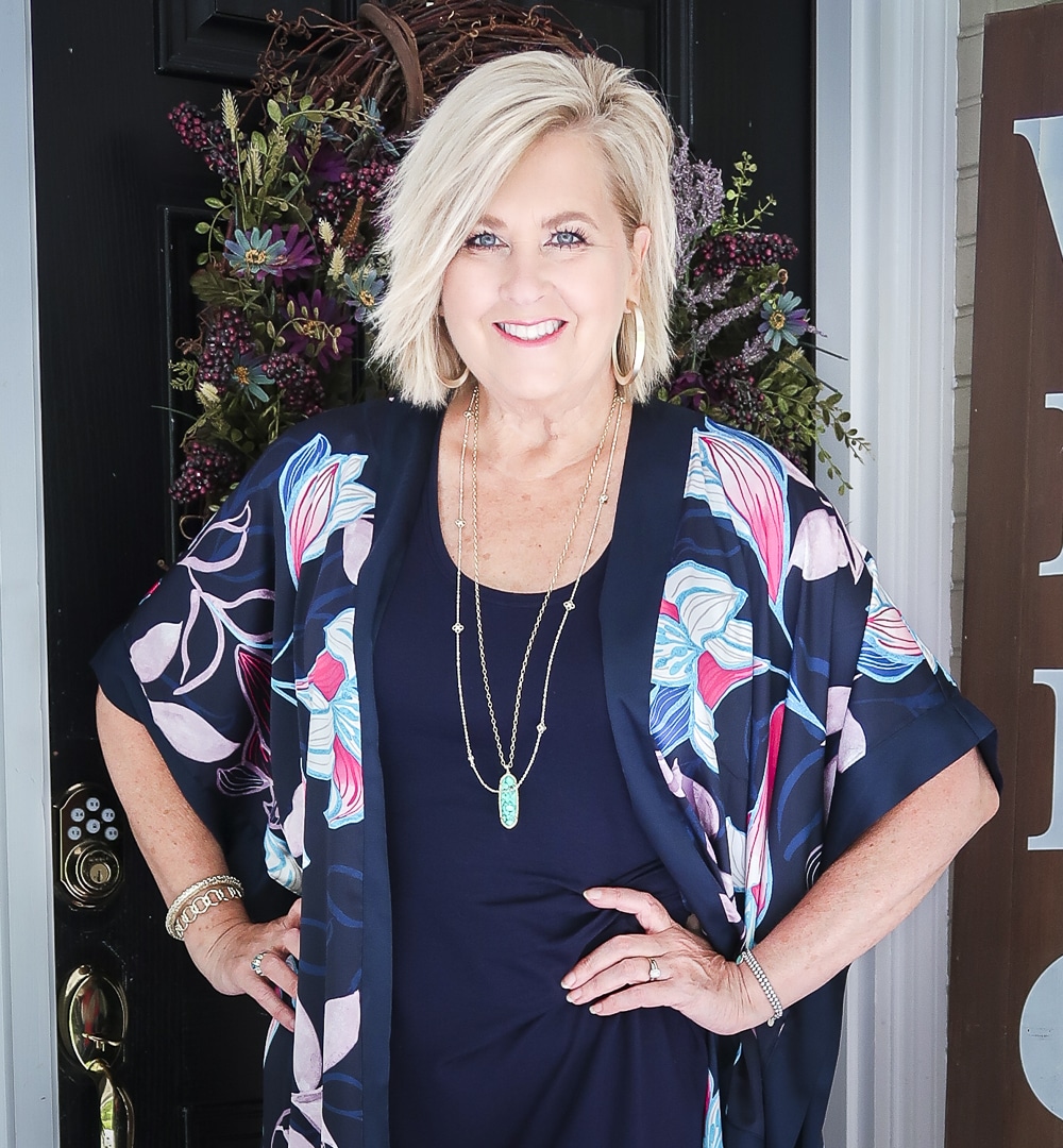 Fashion Blogger 50 Is Not Old is wearing a navy midi dress in all of the seasons. In summer, she added a floral kimono