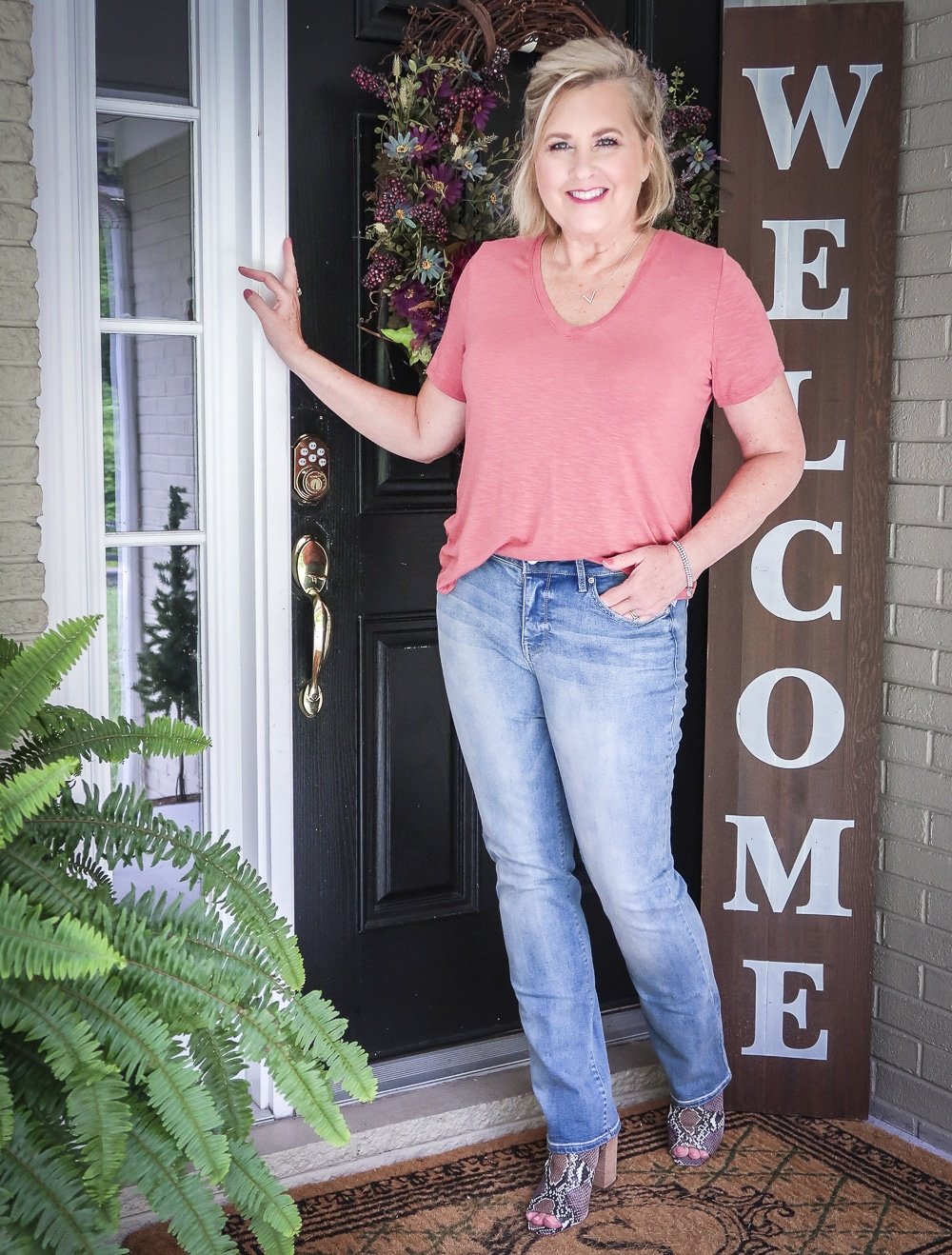 Fashion Blogger 50 Is Not Old is wearing a faded red v-neck t-shirt with a pair of straight leg jeans and brown snakeskin boots